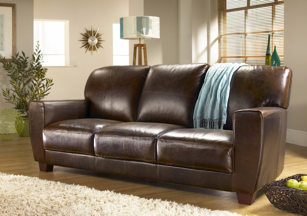 Темно-коричневый диван из кожзама стильно смотрится на фоне светлых стен