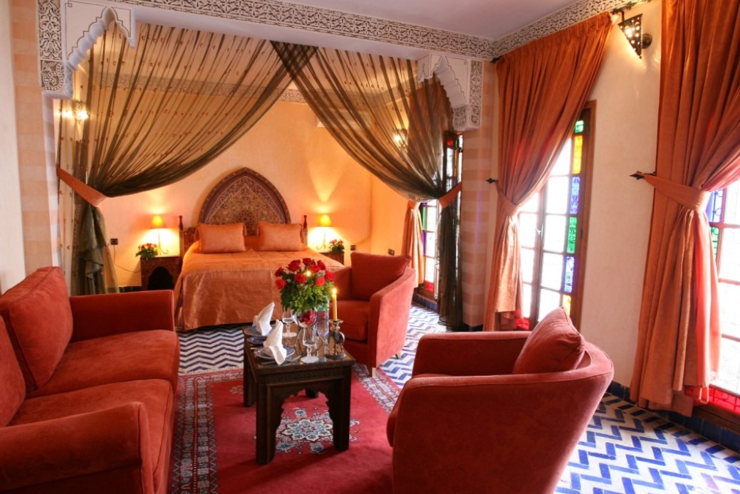 Изголовье в восточном стиле и красные оттенки создают уютную марокканскую спальню