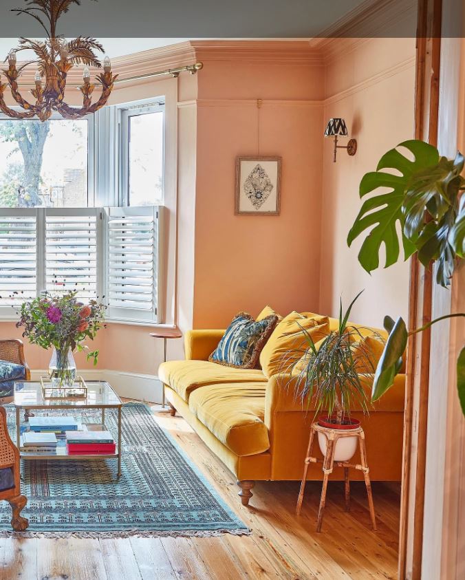 Желтый диван на фоне персиковых стен создает солнечное настроение в гостиной