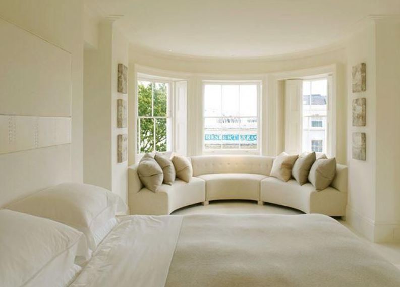 Полукруглый модульный диван перекликается по цвету со светлым интерьером спальни