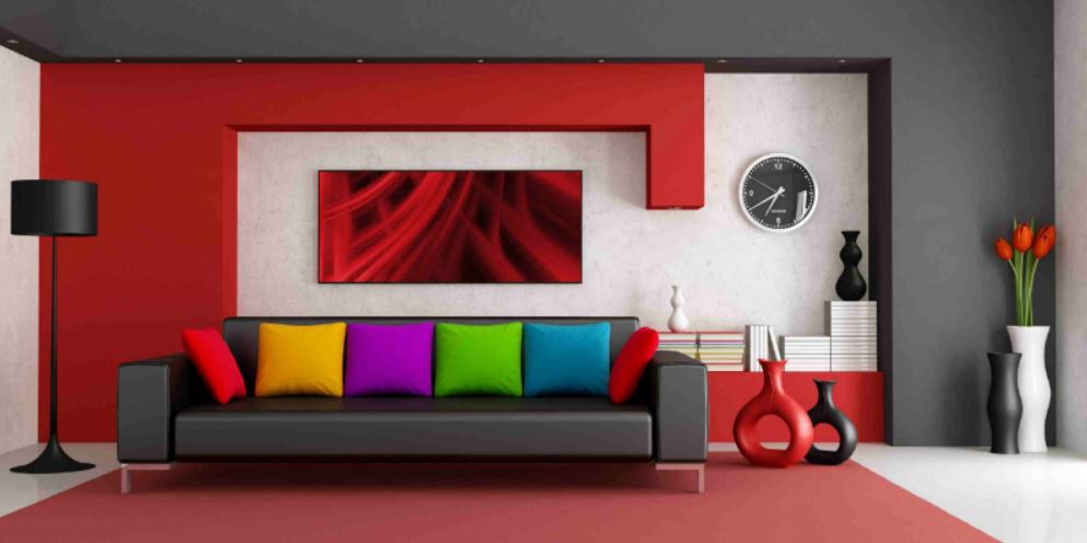 Красные стены и разноцветные подушки приглушает темно-серый кожаный диван