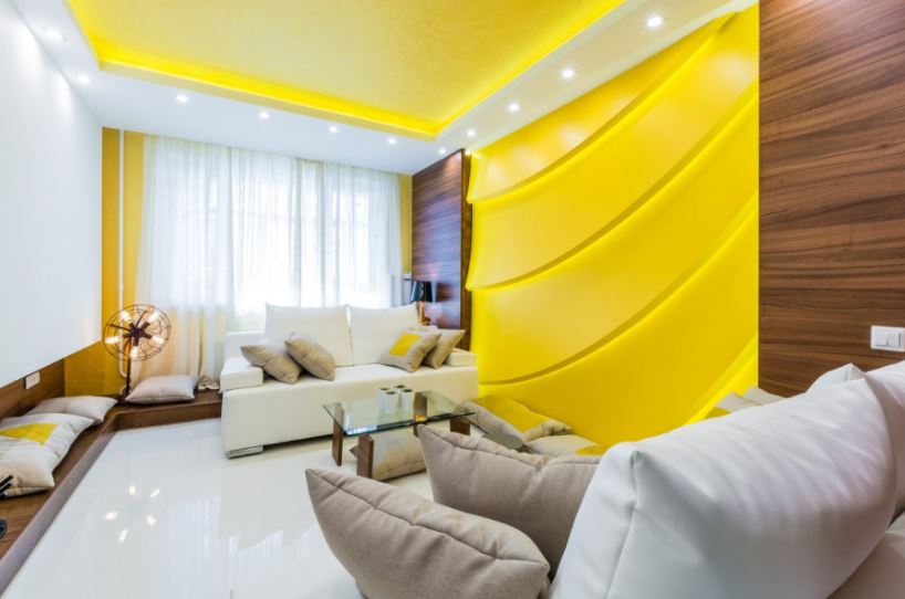 Солнечная гостиная с желтым потолком и акцентом на стенах восполнит недостаток естественного освещения