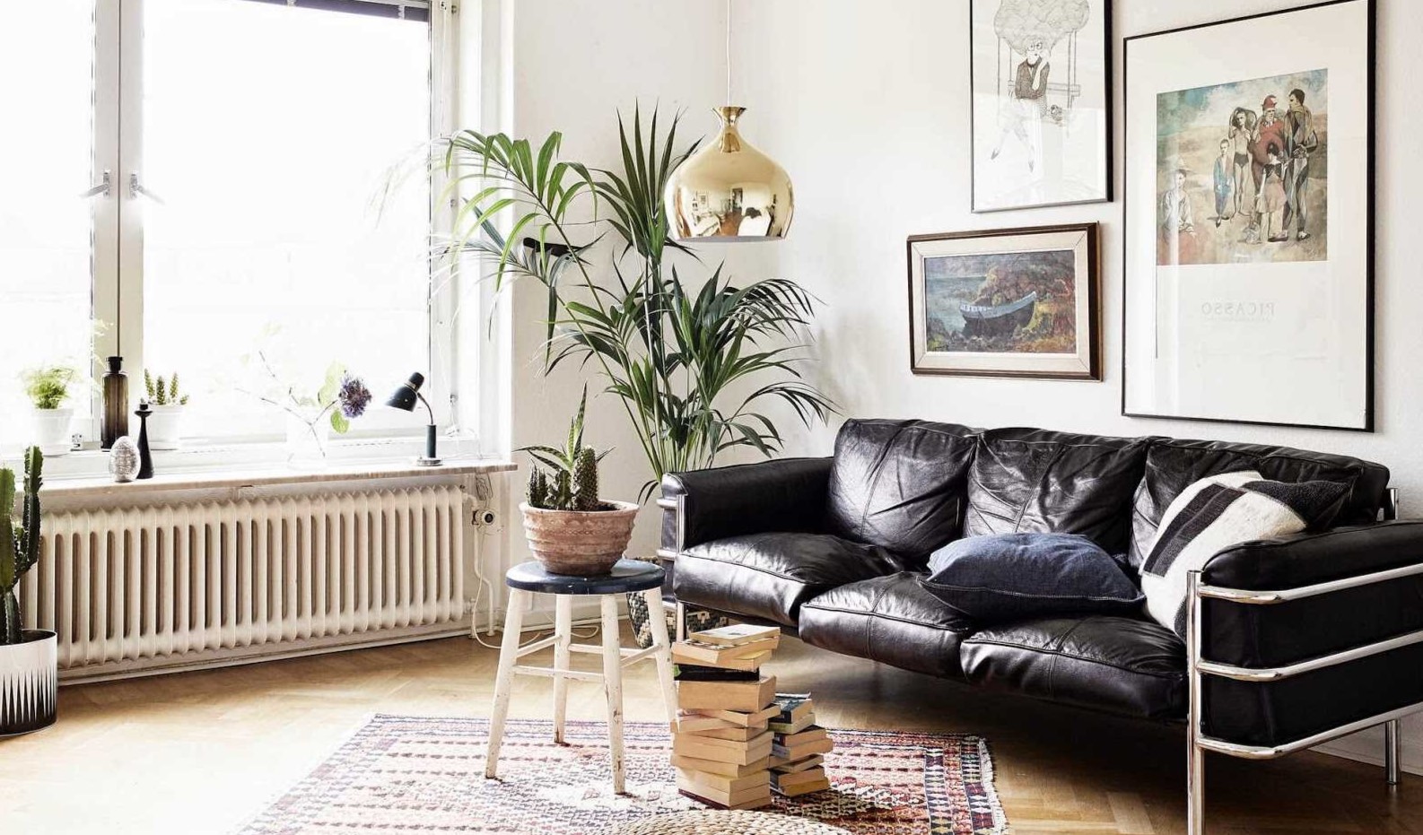Черный кожаный диван стильно смотрится в интерьере светлой комнаты