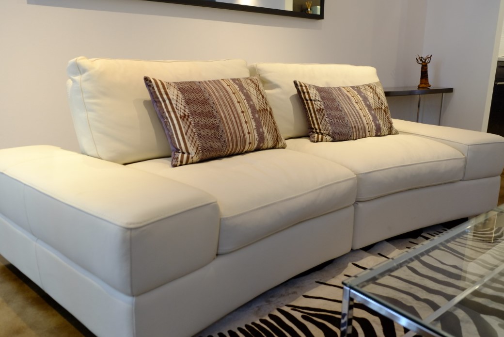 Однотонный кожаный диван можно украсить декоративными подушками с орнаментом