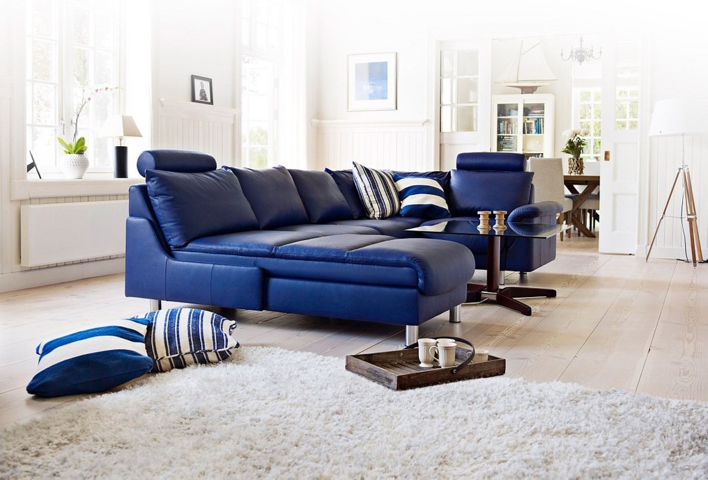 Синий диван является акцентным элементом в светлой гостиной