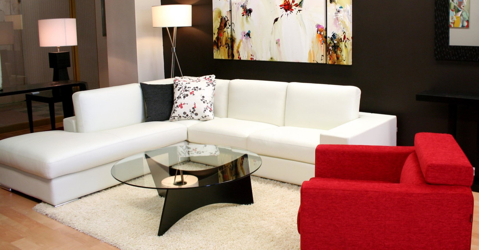 Белый диван стильно смотрится на фоне черной стены и отлично сочетается с красным креслом