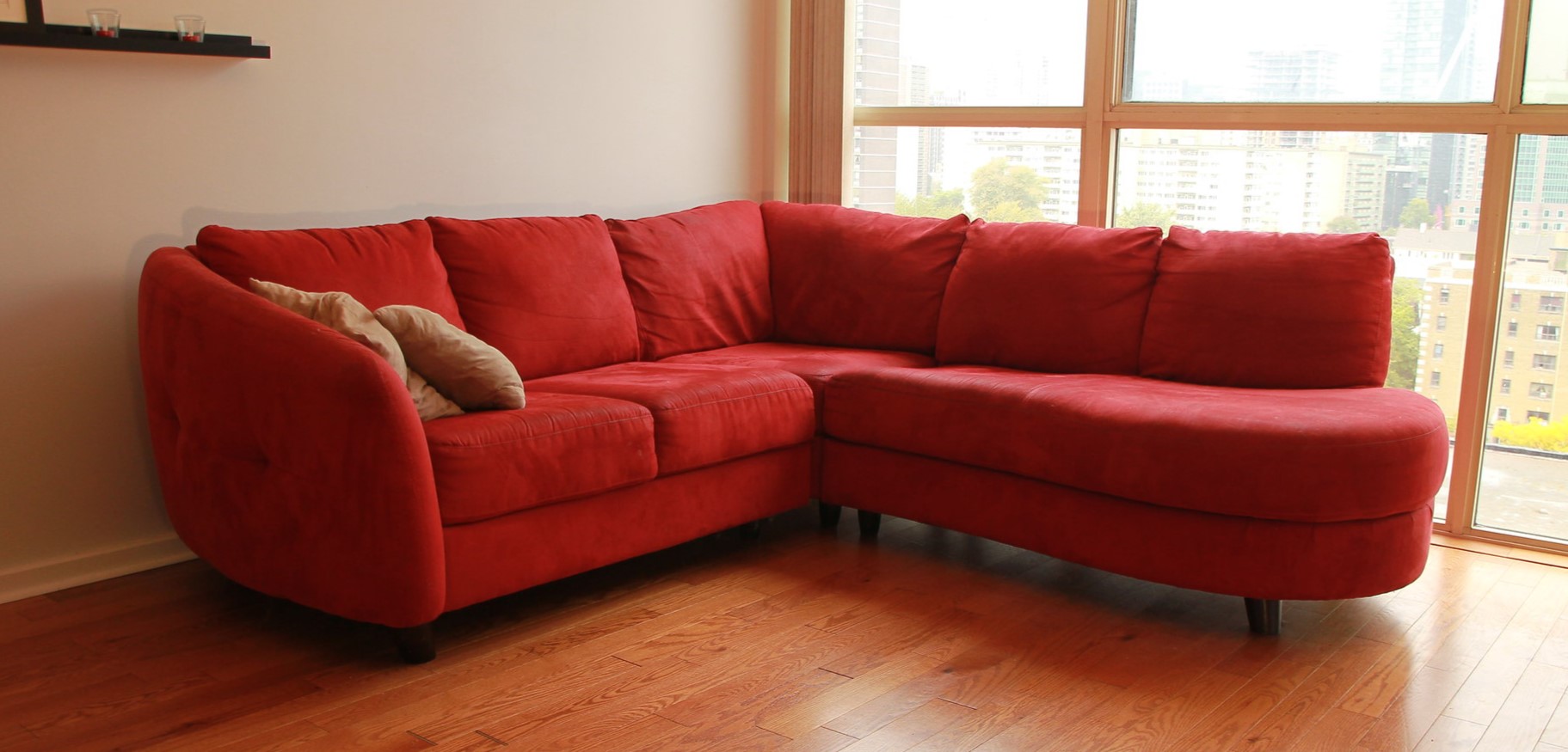 Красный угловой диван можно использовать в качестве акцента в светлой гостиной