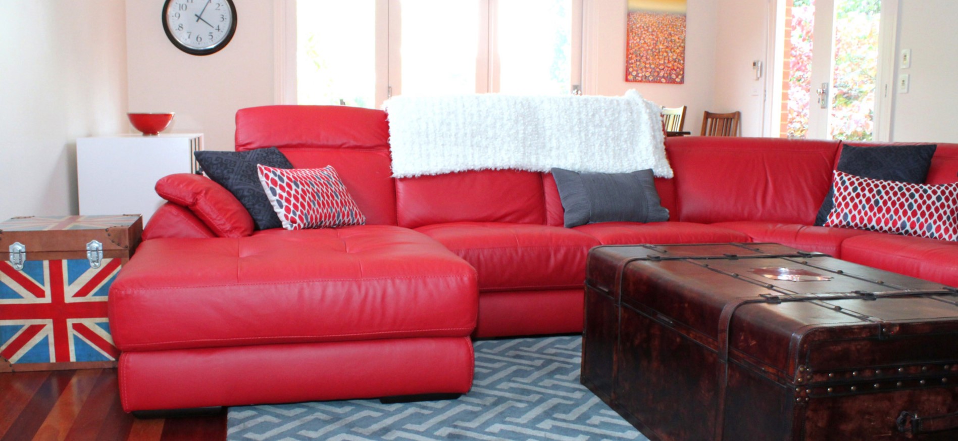 Красный кожаный диван будет стильно смотреться в светлой комнате