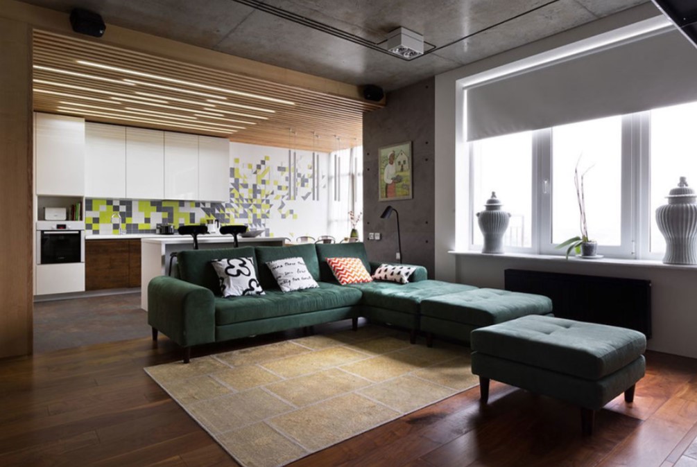Темно-зеленый диван в гостиной можно украсить светлыми подушками с рисунком
