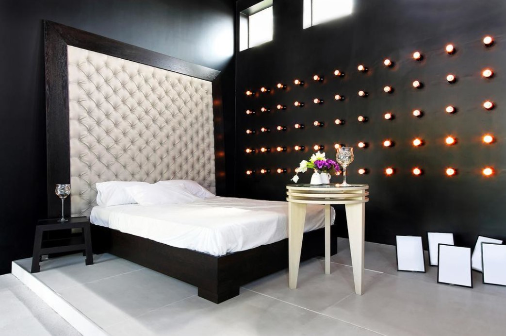 Темную стену в спальне можно декорировать яркими лампочками