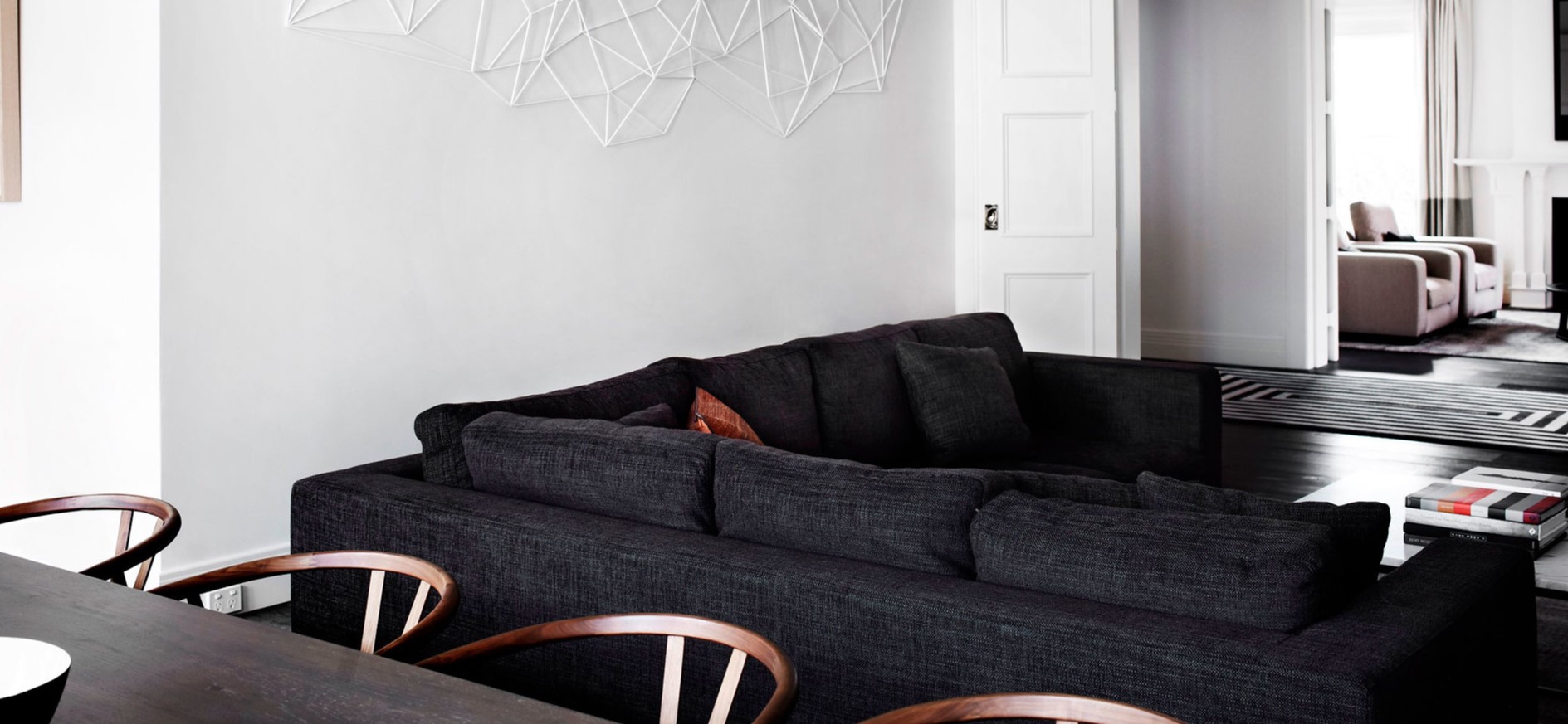 Черный диван стильно смотрится на фоне белых стен