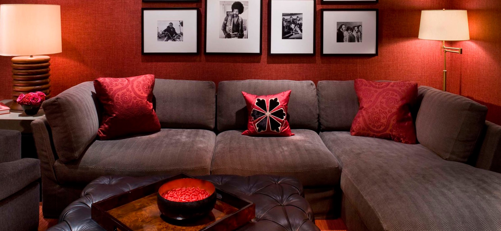 Красные подушки под цвет стен идеально гармонируют с обивкой дивана