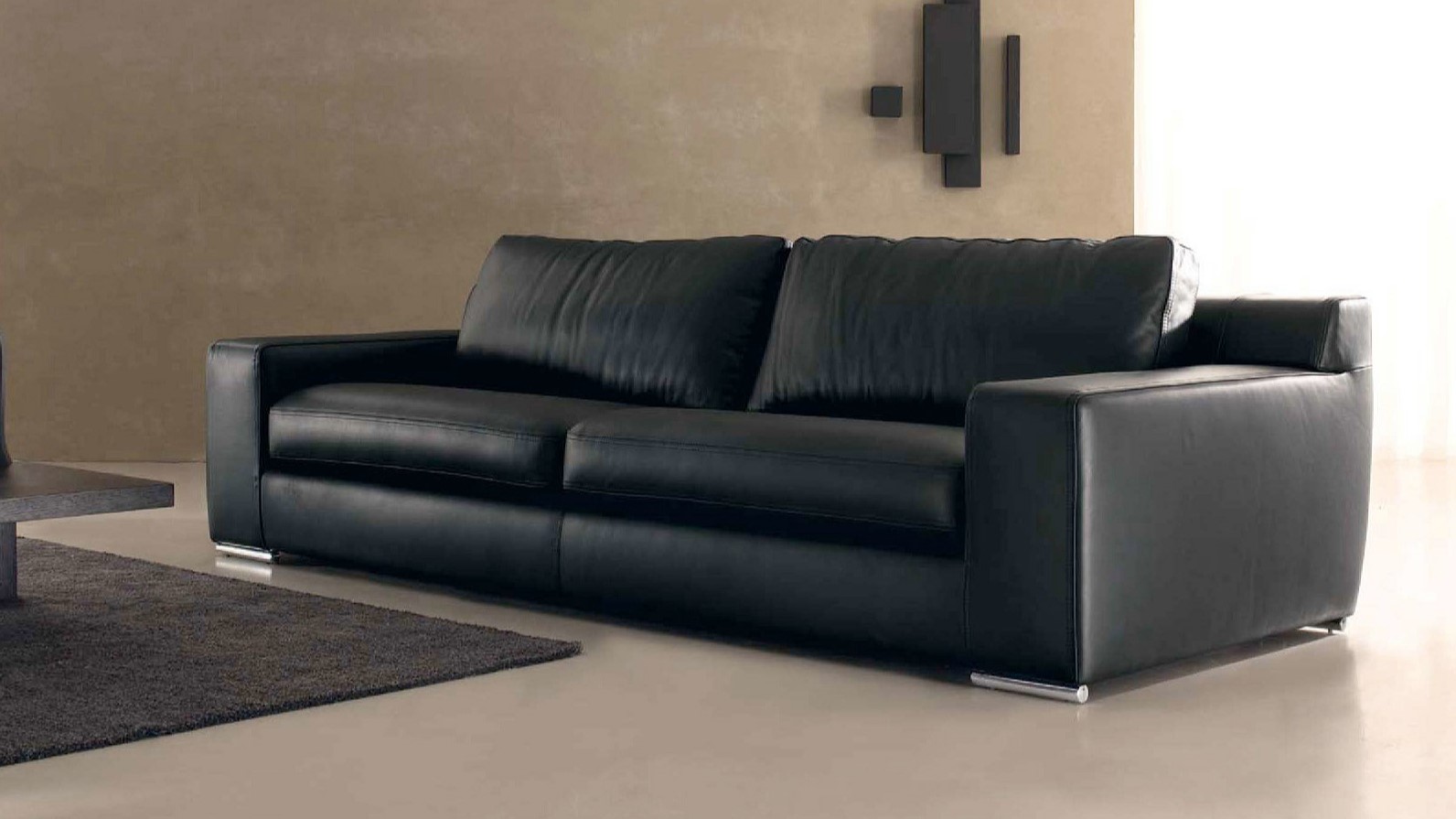 Черный диван с металлическими ножками можно успешно использовать в интерьере хай-тек