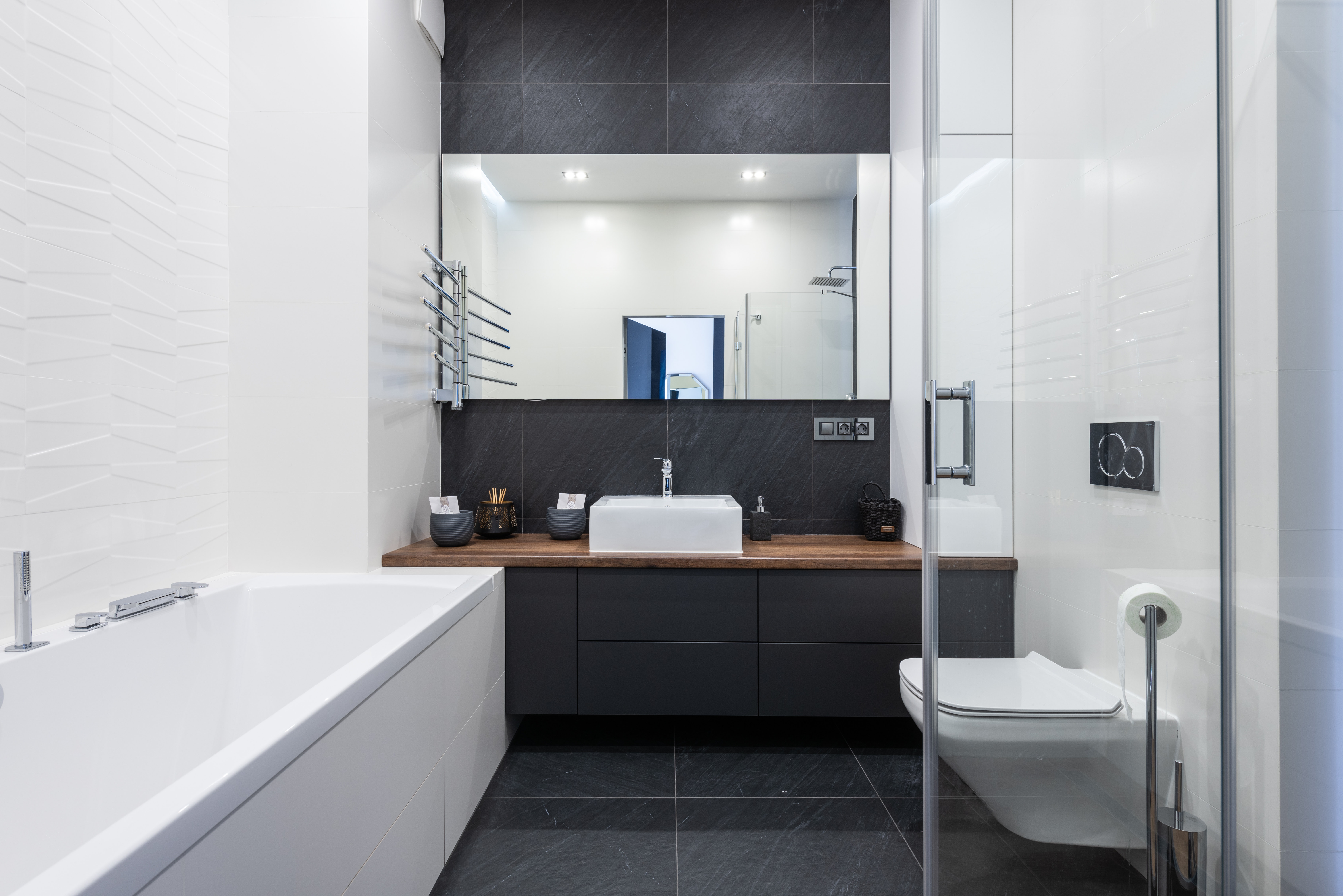Прямоугольное зеркало эффектно смотрится в черно-белой гамме ванной комнаты, визуально делает пространство шире.