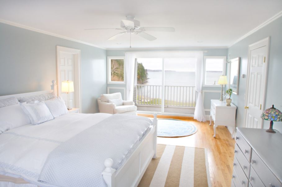 Белая спальня с деревянным полом и акцентными аксессуарами