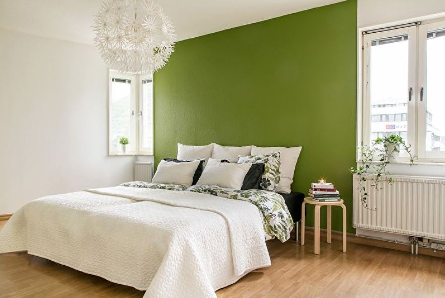 Зеленая стена задает тон белому интерьеру спальни