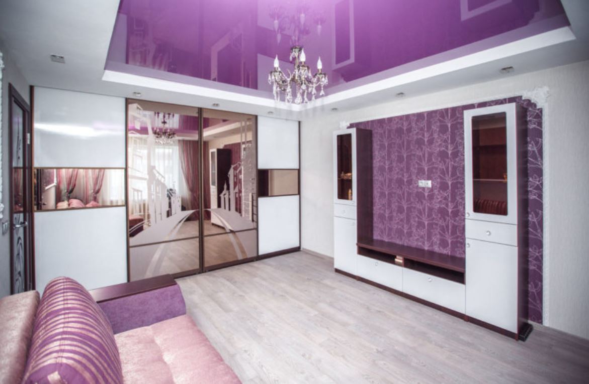 Фиолетовый натяжной потолок и фрагмент стены создают волшебную ауру в гостиной