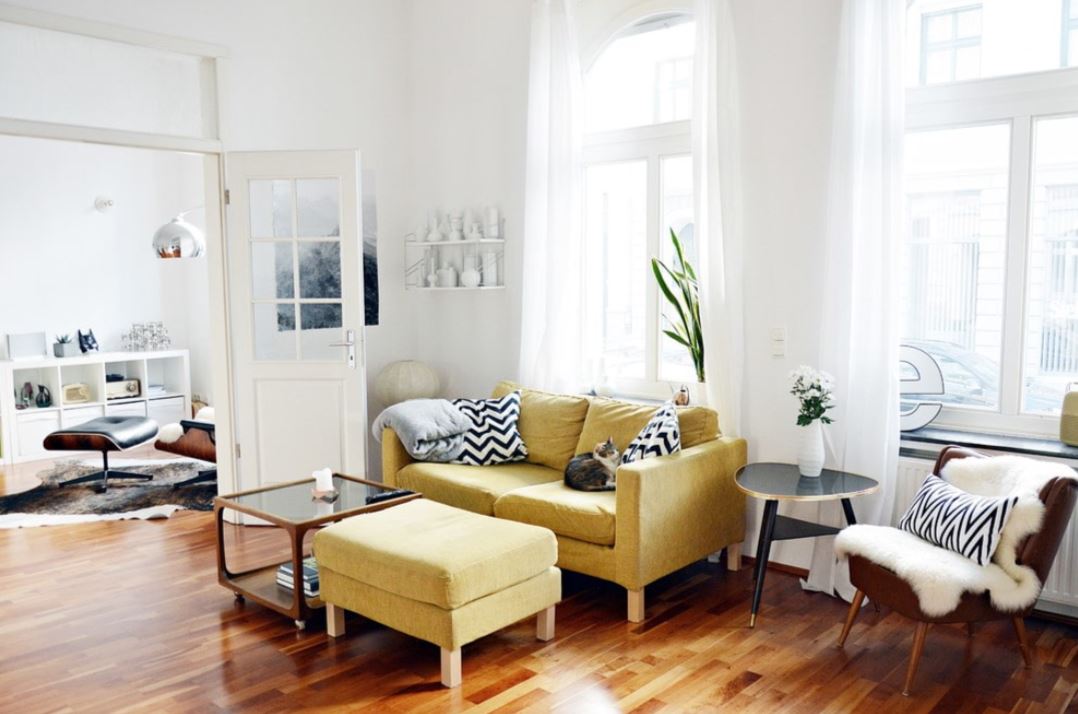 Горчичный цвет дивана оживляет белый интерьер