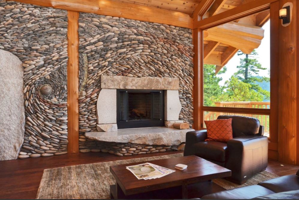 Стена, выложенная речным камнем в виде космического пейзажа, завораживает и отлично гармонирует с деревянной отделкой пола и потолка