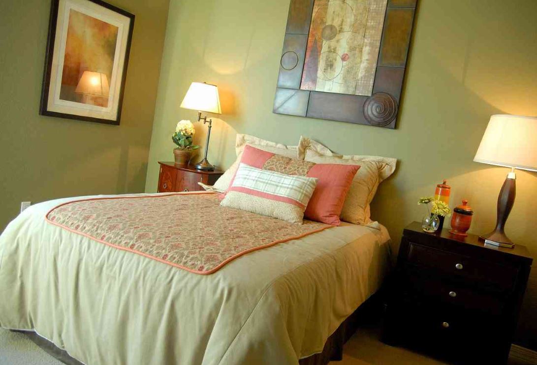 Нежный оливковый и пастельный лососевый гармонично сочетаются в интерьере спальни