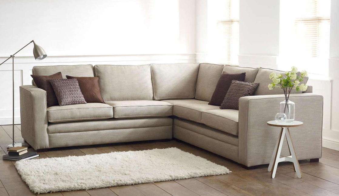 Угловой диван с коричневыми подушками и белый пушистый ковер